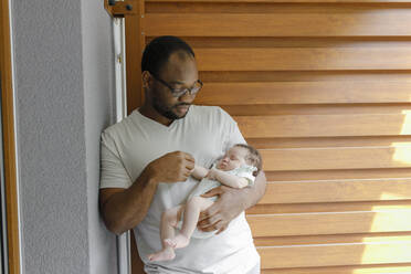 Vater hält die Hand seiner Tochter und lehnt sich an die Wand am Eingang - VIVF00280