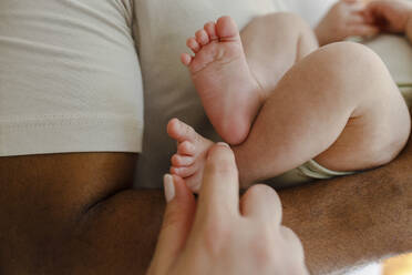 Frau berührt die Füße eines kleinen Mädchens, das vom Vater gehalten wird - VIVF00282