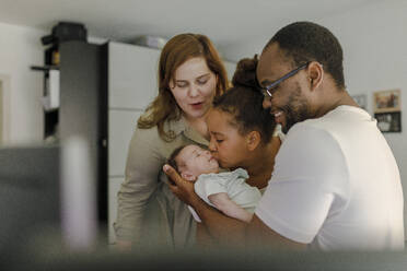 Cheerful mother and father with girl kissing baby sister at home - VIVF00292