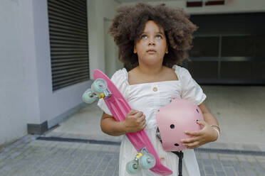 Nachdenkliches Mädchen mit Skateboard und Helm vor einem Eingang stehend - VIVF00312