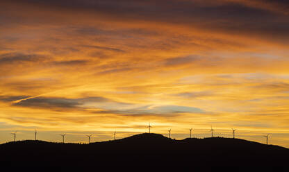 Stimmungsvoller Himmel über Silhouetten von Windkraftanlagen bei Sonnenuntergang - LJF02306