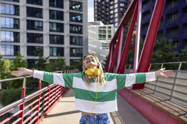 Happy young woman with arms outstretched on walkway - WPEF06706