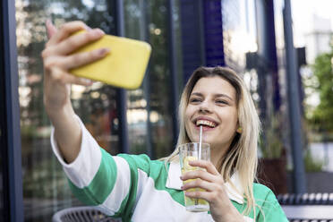 Glückliche junge Frau, die ein Trinkglas hält und ein Selfie mit ihrem Mobiltelefon macht - WPEF06712