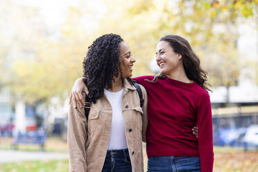 Happy women with arms around in park - WPEF06720