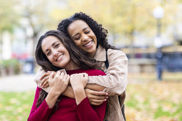 Woman embracing friend in park - WPEF06738