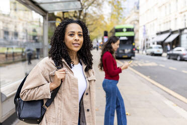 Thoughtful woman waiting for bus on footpath - WPEF06744