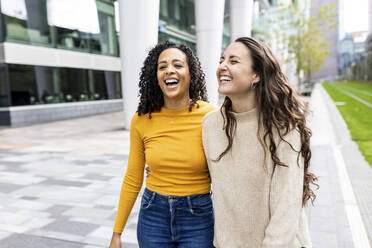 Happy friends walking together outside building - WPEF06763