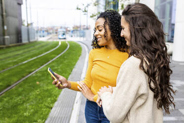 Frau mit Smartphone an den Gleisen stehend - WPEF06765