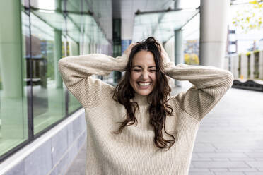 Happy woman with eyes closed standing on footpath - WPEF06769