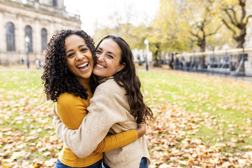 Glückliche Frauen umarmen sich im Herbst im Park - WPEF06789