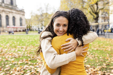 Lächelnde Frau umarmt Freund im Herbst Park - WPEF06791