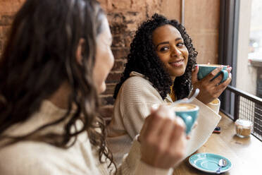 Lächelnde Freunde genießen einen Kaffee im Cafe - WPEF06805