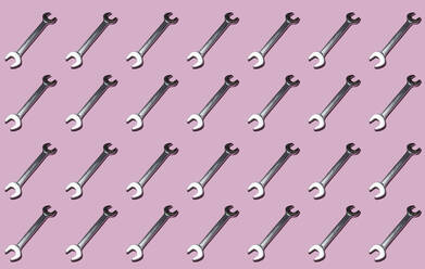 Pattern of rows of wrenches flat laid against pink background - GIOF15679