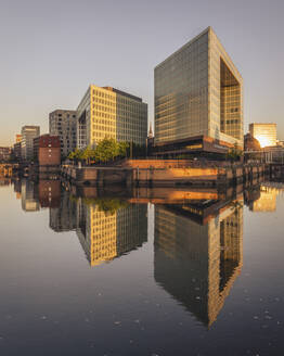 Deutschland, Hamburg, Bürogebäude spiegeln sich in der Elbe in der Abenddämmerung - KEBF02497