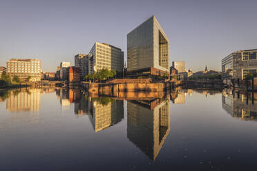 Germany, Hamburg, Office buildings reflecting in Elbe river at dusk - KEBF02500