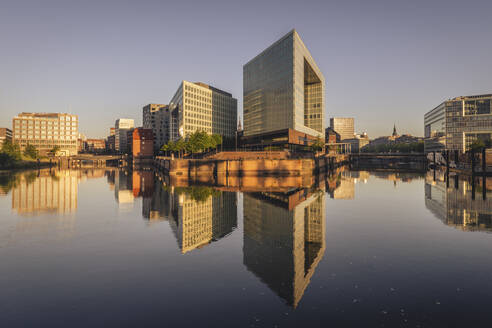 Deutschland, Hamburg, Bürogebäude spiegeln sich in der Elbe in der Abenddämmerung - KEBF02500