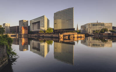 Germany, Hamburg, Office buildings reflecting in Elbe river at dusk - KEBF02501