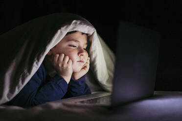 Boy about to fall asleep watching laptop in bedroom - LJF02323