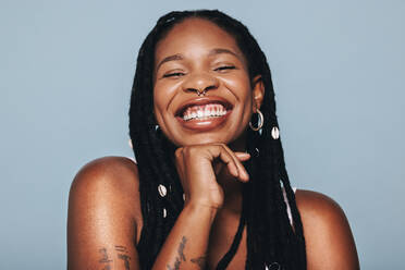 Happy woman with face piercings smiling at the camera in a studio. Young black woman feeling confident in herself. - JLPSF28383