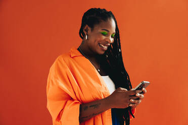 Woman in casual clothing using a smartphone in a studio. Happy young woman enjoying browsing social media. - JLPSF28425