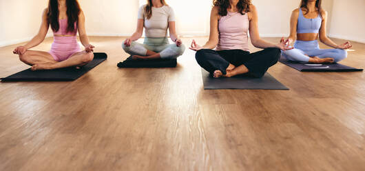 Unbekannte Frauen bei der Sukhasana-Meditation während eines Yogakurses. Frauen unterschiedlichen Alters bei Atemübungen in einem Yogastudio. Eine Gruppe von Frauen beim Training in einem Fitnessstudio. - JLPSF28485