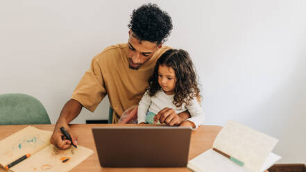 Vater, der seinem kleinen Mädchen zu Hause das Zeichnen mit einem Farbstift beibringt. Liebevoller alleinerziehender Vater, der seine kleine Tochter zu Hause unterrichtet. Vater, der mit seiner Tochter eine kreative Online-Anleitung verfolgt. - JLPSF28625