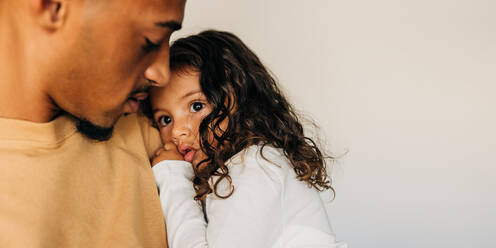 Affectionate single father holding and embracing his daughter in his arms. Loving single dad bonding with his little girl at home. - JLPSF28635