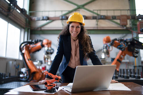 Ein Porträt eines weiblichen Chefingenieurs in einer modernen Industriefabrik, der einen Computer benutzt. - HPIF00707
