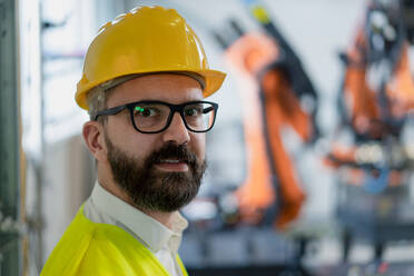 Ein Porträt eines männlichen Chefingenieurs in einer modernen Industriefabrik, der in die Kamera schaut. - HPIF00723