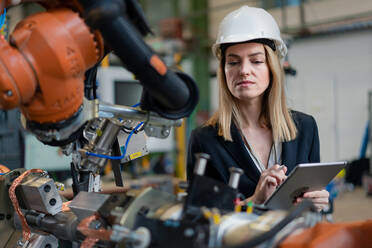 Eine weibliche Chefingenieurin in einer modernen industriellen Fabrik, die ein Tablet benutzt und eine Prüfung durchführt, aus einem langen Blickwinkel. - HPIF00725