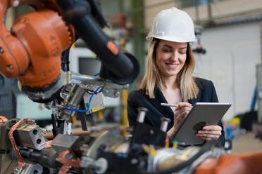 Eine weibliche Chefingenieurin in einer modernen industriellen Fabrik, die ein Tablet benutzt und eine Prüfung durchführt, aus einem langen Blickwinkel. - HPIF00726