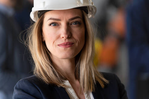 Ein Porträt eines weiblichen Chefingenieurs in einer modernen Industriefabrik, der in die Kamera schaut. - HPIF00733