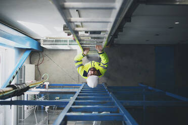 A top view of engineer in industrial factory climbing up the ladder. - HPIF00755