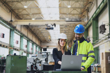 A male and female industrial engineers discussing factory's new machinery project and using laptop. - HPIF00765