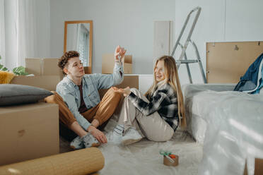 Ein fröhliches junges Paar in seiner neuen Wohnung, das den Umzug plant. - HPIF00785