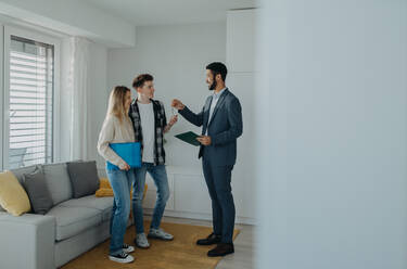 A happy young couple buying their new home and receiving keys from real estate agent - HPIF00818