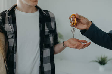 Ein glückliches junges Paar, das sein neues Haus kauft und die Schlüssel vom Immobilienmakler erhält - HPIF00819