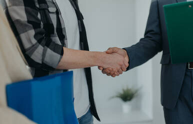 Nahaufnahme eines jungen Paares, das einem Immobilienmakler beim Kauf seines neuen Hauses die Hand schüttelt. - HPIF00820