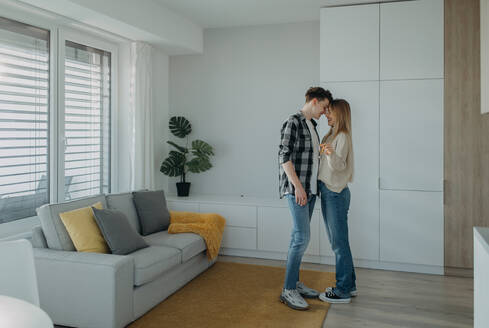 Ein fröhliches junges Paar in seiner neuen Wohnung, stehend und mit Schlüsseln in der Hand, Vorstellung eines Umzugs. - HPIF00823