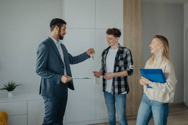 A happy young couple buying their new home and receiving keys from real estate agent - HPIF00824