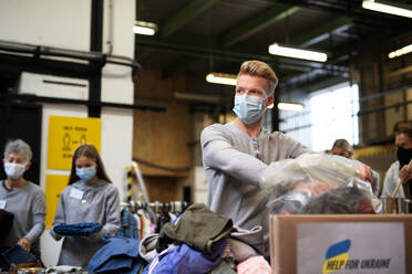 Volunteers sorting out donated clothes for the needs of the Ukrainian migrants, humanitarian aid concept. - HPIF00843