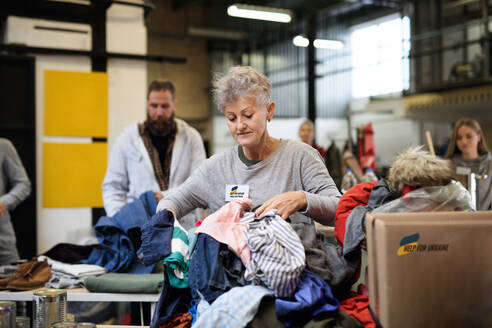 Freiwillige sortieren gespendete Kleidung für den Bedarf der ukrainischen Migranten, Konzept der humanitären Hilfe. - HPIF00845