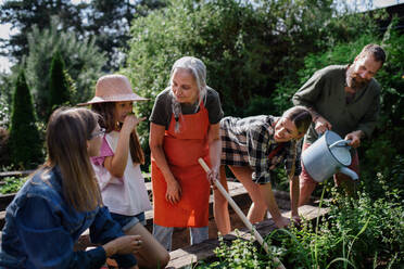 Eine glückliche Bauernfamilie bei der Arbeit mit Gartengeräten im Freien auf einem Gemeinschaftshof. - HPIF00863