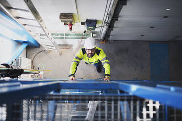 Draufsicht auf einen Ingenieur in einer Industrieanlage, der die Leiter hinaufsteigt. - HPIF00896