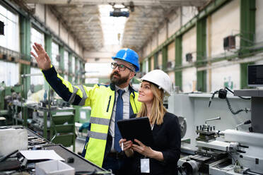 A male and female industrial engineers discussing factory's new machinery project and using laptop. - HPIF00905