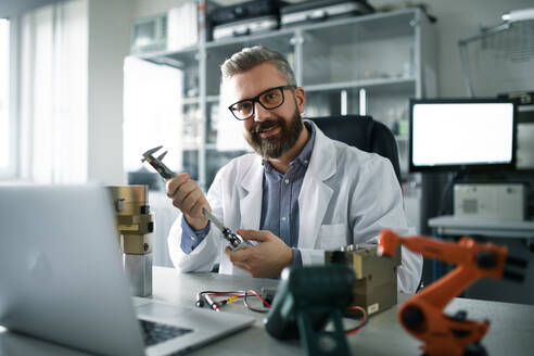 A robotics engineer working on desing of modern robotic arm adn sitting at dest in laboratory. - HPIF00923