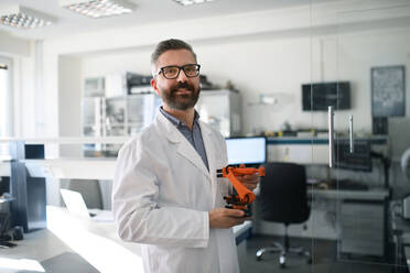 Robotics engineer man holding modern robotic arm in laboratory office. - HPIF00933