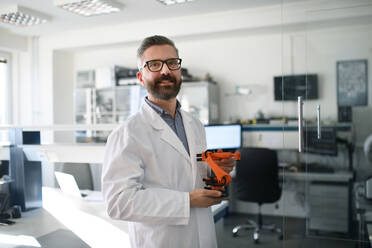 Robotik-Ingenieur Mann hält modernen Roboterarm im Labor Büro. - HPIF00933