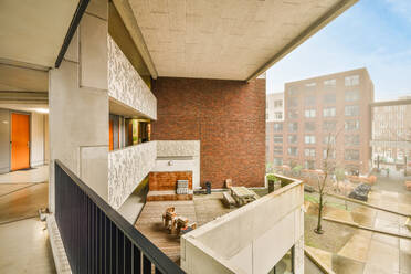 Metallgitterzaun auf dem Balkon eines modernen Wohnhauses mit geöffneter Tür vor blauem Himmel und hohen Häusern in der Stadt - ADSF40374