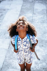 From above African american cute girl with backpack enjoying sun on street in bright day - ADSF40437
